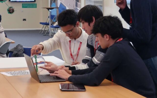 a group of students work together on a laptop